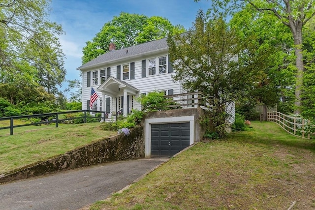 colonial inspired home featuring a garage, asphalt driveway, and a chimney