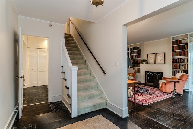 stairs with wood finished floors, ornamental molding, and baseboards