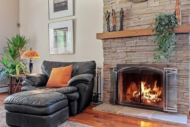 living area with a lit fireplace and wood finished floors