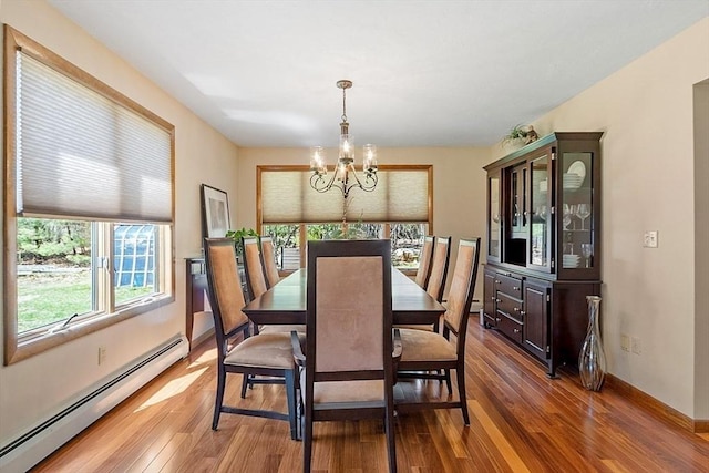 dining space with hardwood / wood-style flooring, a notable chandelier, a baseboard radiator, and baseboards