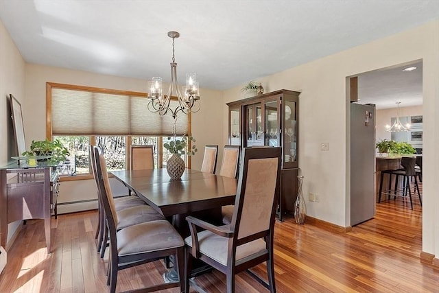 dining area featuring light wood-style flooring, a notable chandelier, baseboards, and baseboard heating
