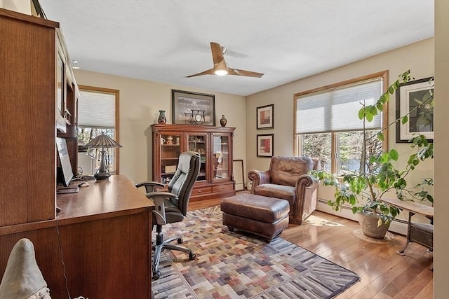 office with a baseboard heating unit, a ceiling fan, plenty of natural light, and hardwood / wood-style flooring