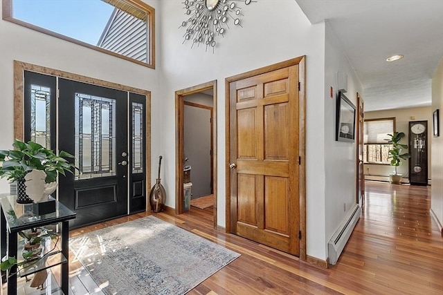 foyer featuring a healthy amount of sunlight, a baseboard heating unit, and wood finished floors