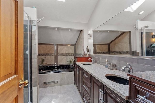 bathroom featuring vaulted ceiling with skylight, a garden tub, a sink, and visible vents