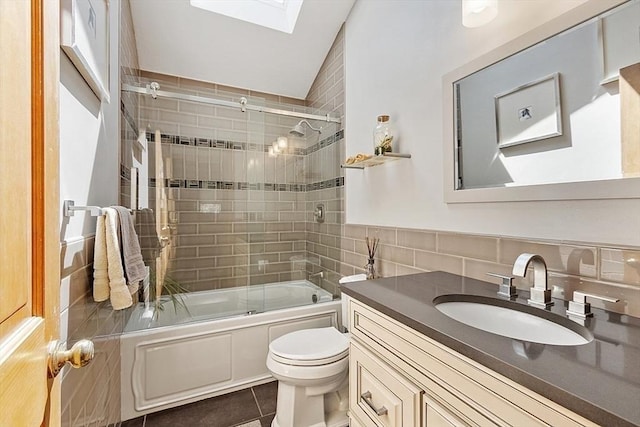 full bath with vanity, tile patterned flooring, toilet, a skylight, and tile walls
