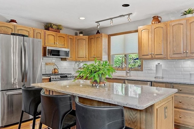 kitchen with a breakfast bar, a center island, a sink, stainless steel appliances, and backsplash