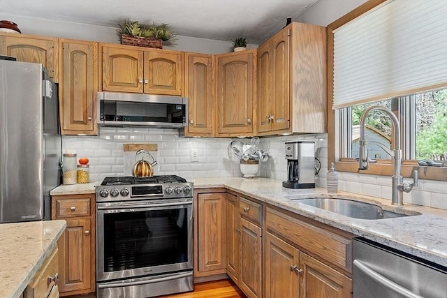 kitchen with light stone countertops, a sink, and appliances with stainless steel finishes