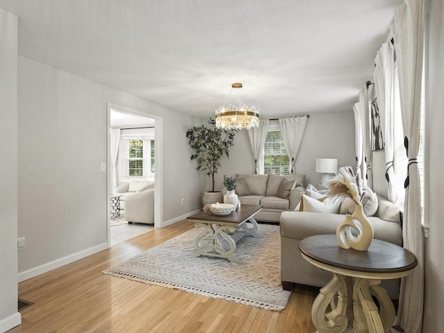 living room with a notable chandelier, plenty of natural light, and light wood-type flooring