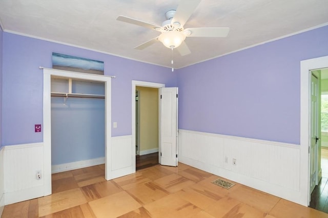 28 River St, Erving, MA 01344 - unfurnished bedroom featuring a wainscoted wall, a closet, a ceiling fan, and ornamental molding