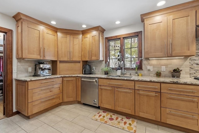 kitchen featuring tasteful backsplash, dishwasher, light stone countertops, a sink, and light tile patterned flooring