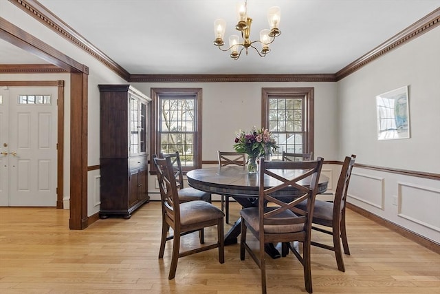 dining space featuring light wood-type flooring, a wealth of natural light, wainscoting, and crown molding