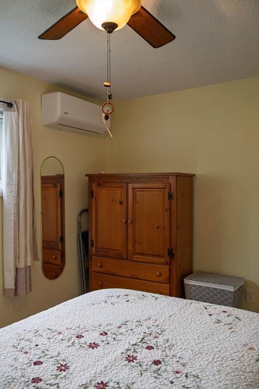 61 Outer Dr Unit 61, Chicopee, MA 01022 - bedroom featuring a wall mounted air conditioner, a textured ceiling, and ceiling fan