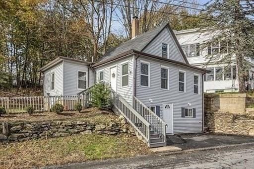 view of front of home with stairway, fence, and a chimney
