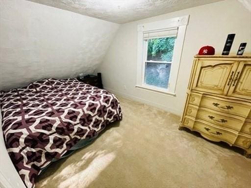 bedroom with baseboards, a textured ceiling, lofted ceiling, and light carpet