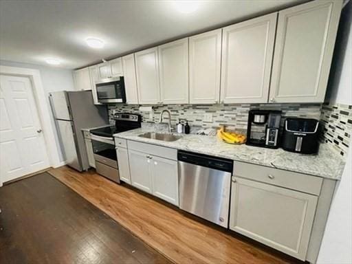 kitchen featuring a sink, backsplash, stainless steel appliances, and wood finished floors