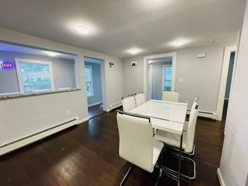 unfurnished dining area with dark wood-type flooring, a baseboard radiator, and baseboards