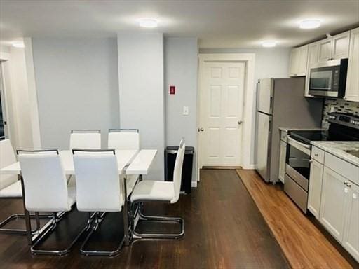 kitchen with dark wood finished floors, appliances with stainless steel finishes, and white cabinetry