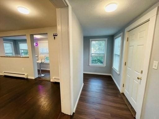 hallway with baseboards, a baseboard heating unit, and dark wood-type flooring