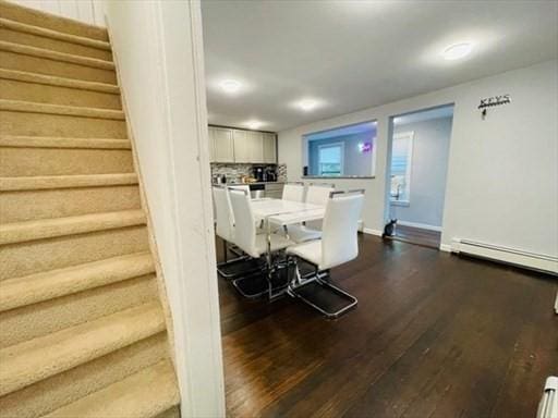 dining space with dark wood-style flooring, baseboards, stairway, and a baseboard radiator