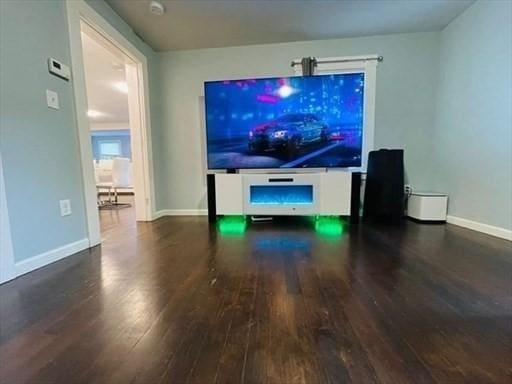 unfurnished living room with baseboards and wood finished floors
