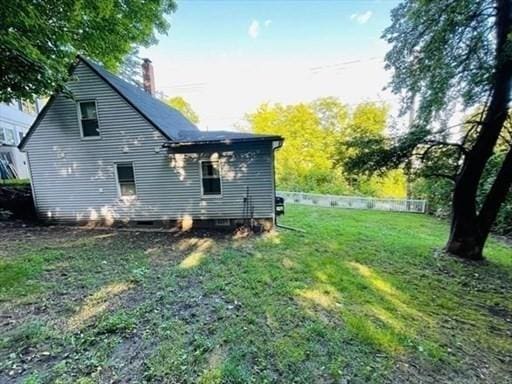 back of house featuring a lawn and a chimney