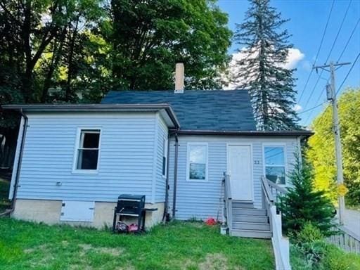 rear view of house featuring entry steps and a yard