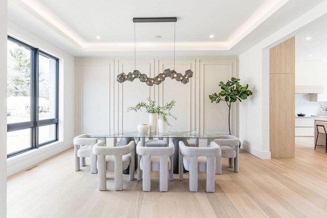 dining room featuring light wood-type flooring, visible vents, a raised ceiling, recessed lighting, and baseboards