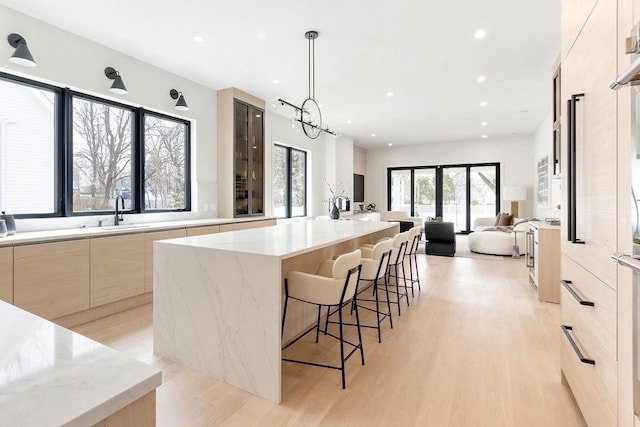 kitchen with a sink, light wood-style floors, a spacious island, and modern cabinets