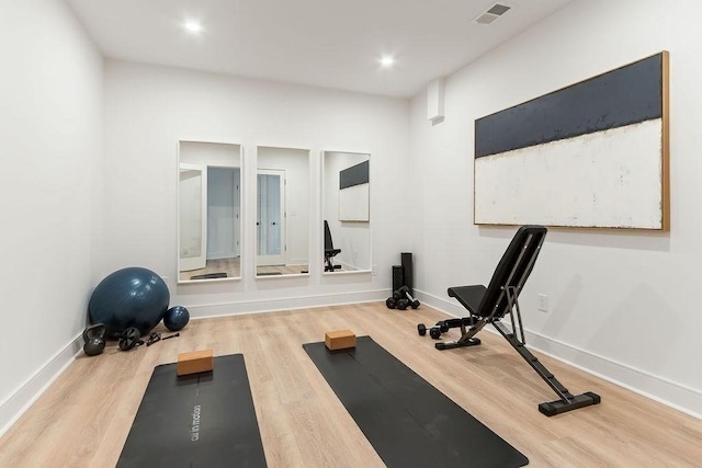 workout area with visible vents, baseboards, and wood finished floors