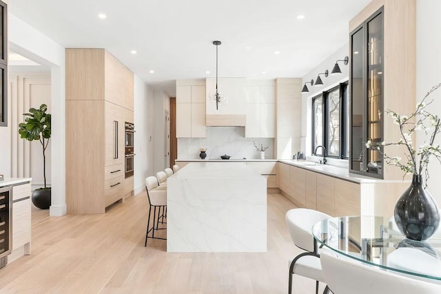 kitchen featuring light brown cabinets, a kitchen bar, light countertops, light wood-style flooring, and modern cabinets