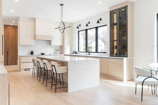 kitchen with a kitchen island, backsplash, modern cabinets, and a kitchen bar