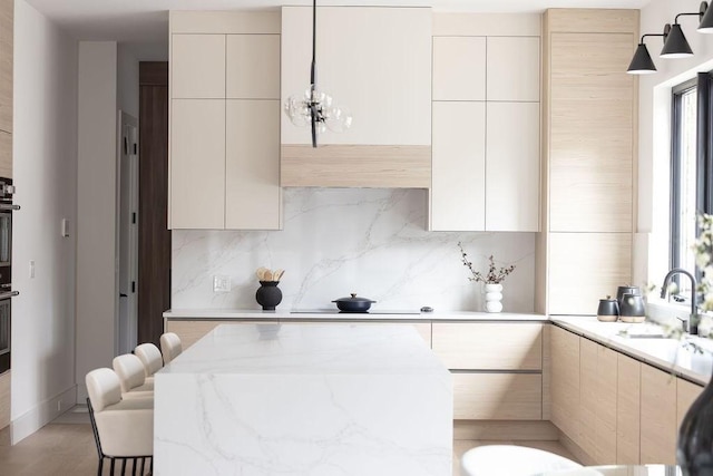 kitchen featuring light stone counters, modern cabinets, backsplash, and a sink