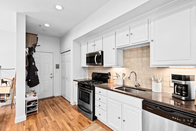kitchen featuring decorative backsplash, light wood-style floors, white cabinets, a sink, and stainless steel appliances