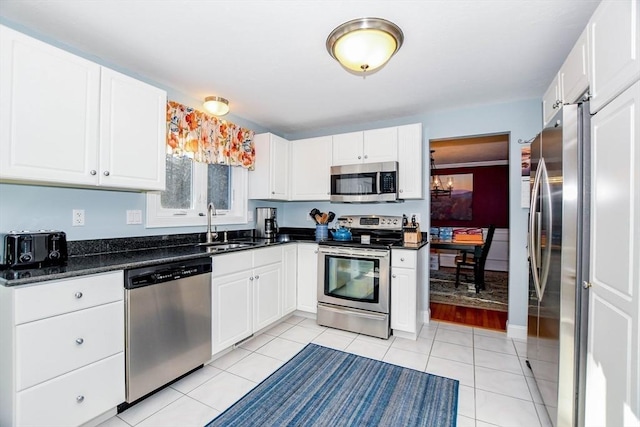 kitchen with white cabinetry, sink, dark stone counters, light tile patterned floors, and stainless steel appliances