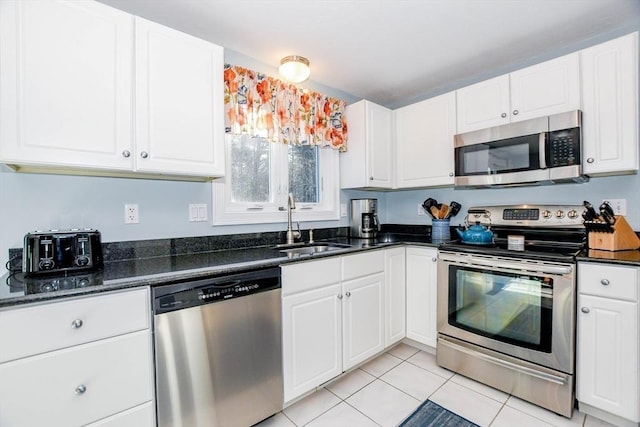 kitchen with light tile patterned floors, stainless steel appliances, sink, and white cabinets