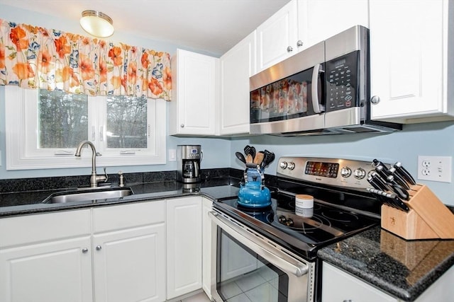 kitchen with white cabinetry, appliances with stainless steel finishes, sink, and dark stone countertops