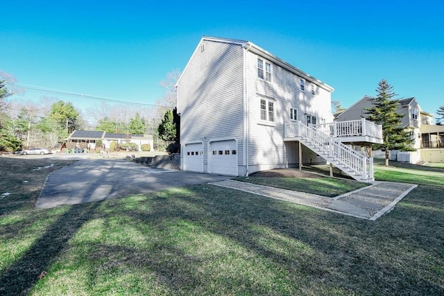 exterior space with a garage, a wooden deck, and a yard