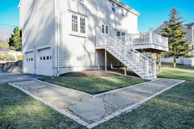 back of house with a wooden deck, a garage, and a lawn