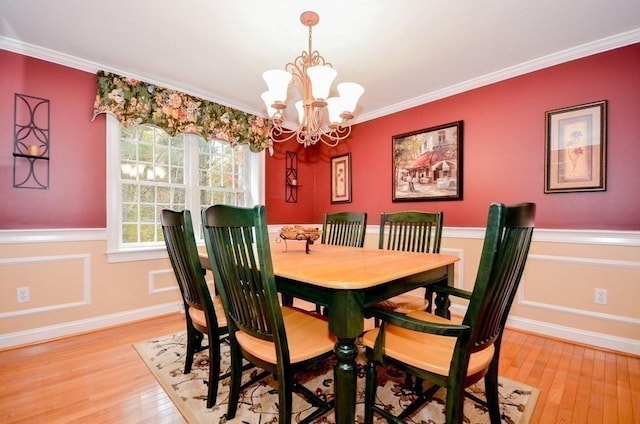 dining area featuring ornamental molding, an inviting chandelier, and light hardwood / wood-style floors