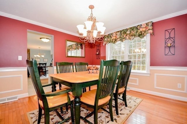 dining space with crown molding, wood-type flooring, and a notable chandelier