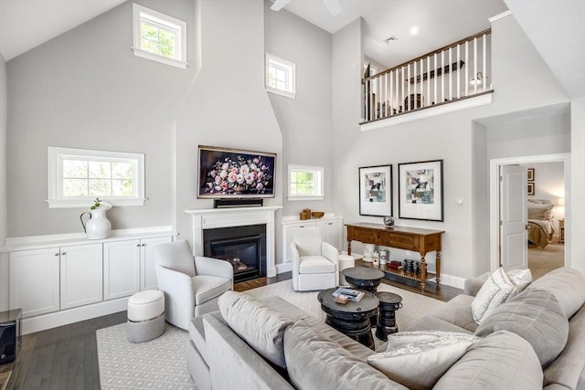 41 Old Main Rd Unit 3A, Falmouth, MA 02556 - living room featuring a towering ceiling, dark wood-type flooring, a glass covered fireplace, and baseboards