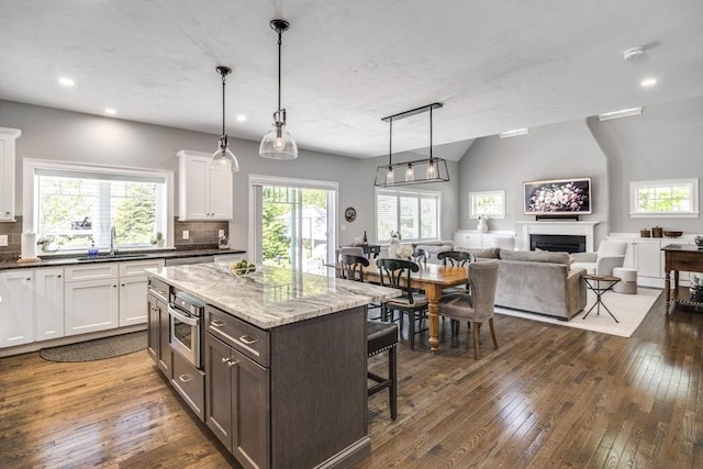 41 Old Main Rd Unit 3A, Falmouth, MA 02556 - kitchen featuring a sink, a kitchen breakfast bar, open floor plan, a fireplace, and white cabinets