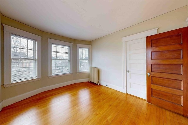 unfurnished room featuring radiator and light hardwood / wood-style flooring