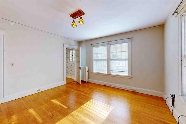 empty room with radiator heating unit and light wood-type flooring