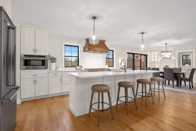 13 Alden Rd, Andover, MA 01810 - kitchen featuring a sink, light wood-type flooring, a breakfast bar, appliances with stainless steel finishes, and premium range hood