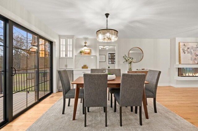 13 Alden Rd, Andover, MA 01810 - dining space featuring baseboards, light wood-type flooring, a multi sided fireplace, and an inviting chandelier