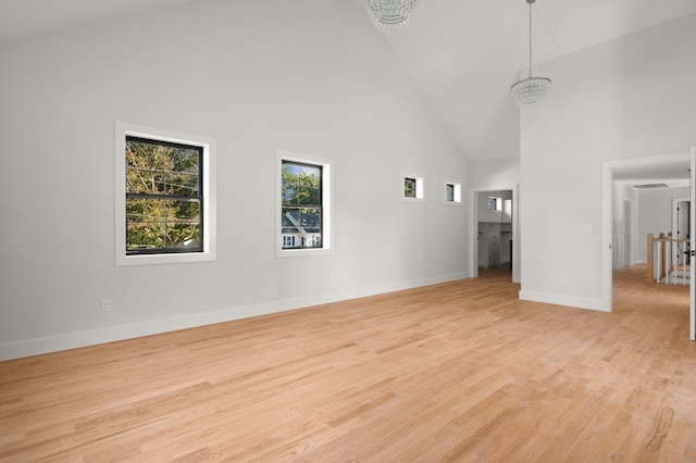 unfurnished living room with a chandelier, high vaulted ceiling, and light hardwood / wood-style flooring