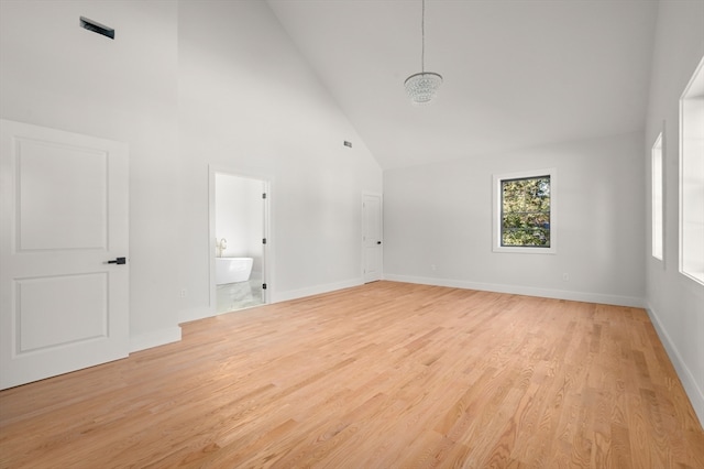 unfurnished room with light wood-type flooring and high vaulted ceiling