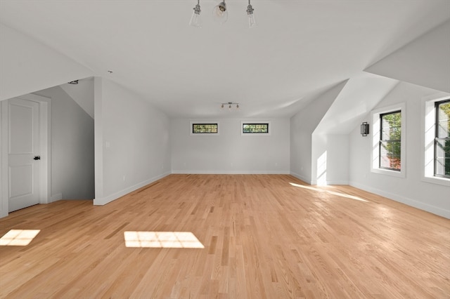 additional living space featuring light wood-type flooring and lofted ceiling