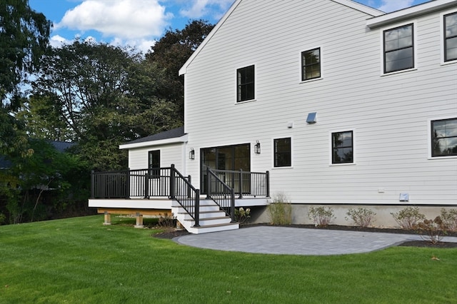 back of house with a wooden deck, a lawn, and a patio area